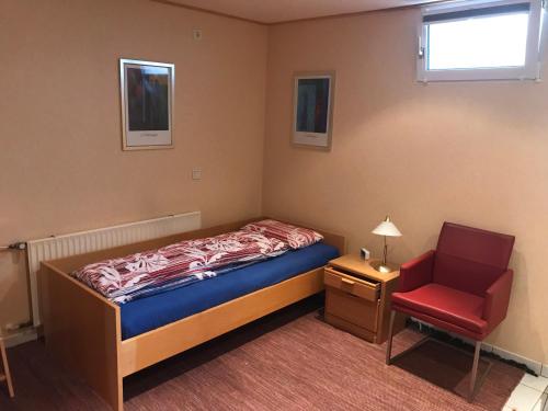 SpabrückenFerienwohnung Inga的一间小卧室,配有一张床和一把红色椅子