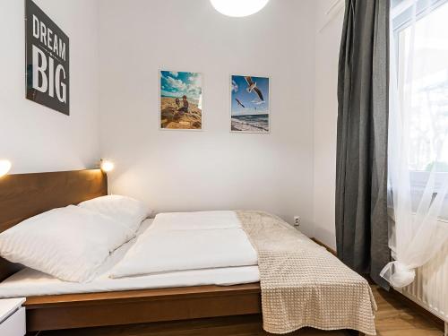 科沃布热格VacationClub - Olymp Apartment 502A的卧室配有一张铺有白色床单的床和墙上的海报