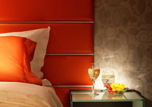 香港香港丽悦酒店的一张带红色床头板和两杯葡萄酒的床