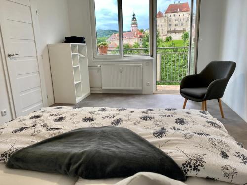 捷克克鲁姆洛夫CK-Apartment的卧室配有床、椅子和窗户。