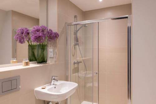 曼彻斯特Cove Minshull Street的浴室配有水槽和带紫色花卉的淋浴。