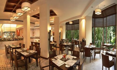 孟买The Leela Mumbai的用餐室设有桌椅和窗户。