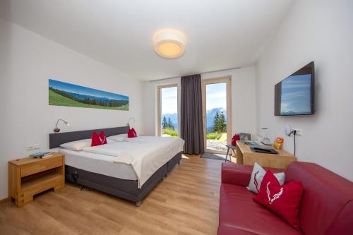 滨湖采尔Schmiedhof Alm的一间卧室配有一张床和一张红色的沙发