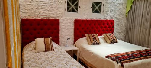 萨尔塔帕拉西奥埃斯孔迪多部门精品酒店的一间卧室配有两张带红色床头板的床
