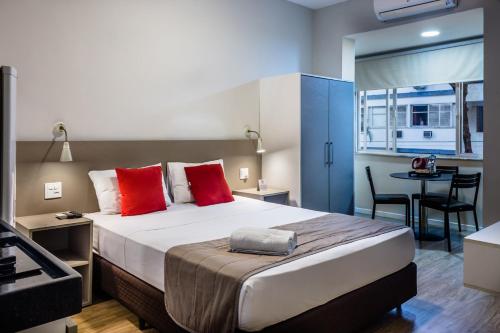 里约热内卢伊帕内玛殷乔伊公寓式酒店的一间卧室配有一张带红色枕头的大床