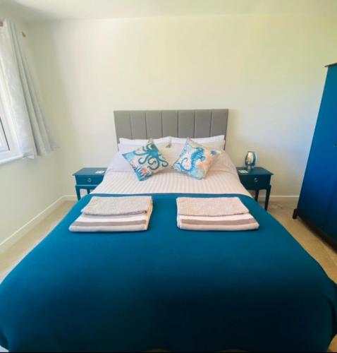 布德Eagle House Holiday Let的蓝色的床,上面有三条毛巾