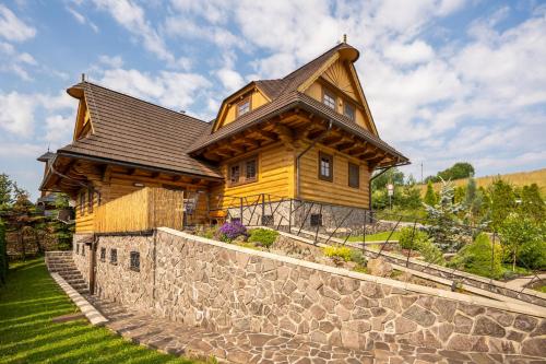 斯祖贝莱克Chalet Zuberec, 5 apartments, jacuzzi, sauna, mountains的石墙顶部的大型木制房屋