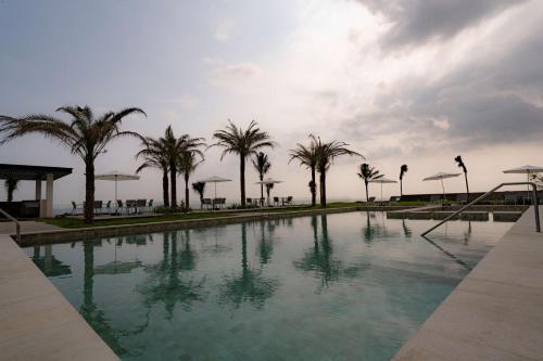 韦拉克鲁斯Best Western Plus Riviera Veracruz的棕榈树和云天的游泳池