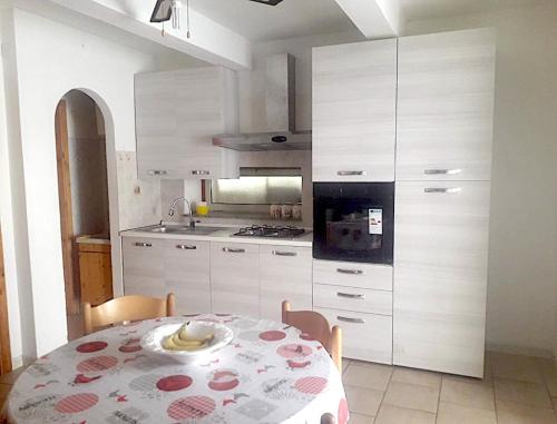 特罗佩阿Casa Vacanze Calabria的一间带桌子的厨房和一间带白色橱柜的厨房