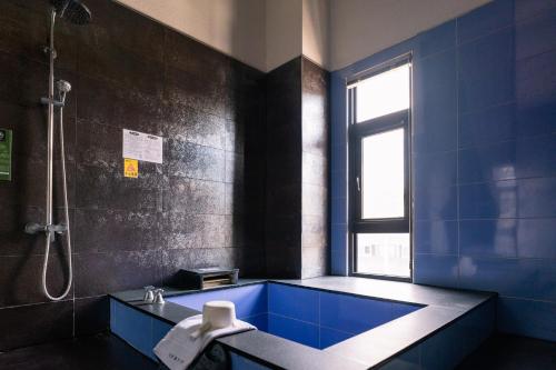 礁溪58度温泉汤苑会馆的一间带蓝色浴缸和淋浴的浴室
