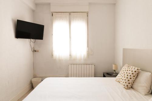 毕尔巴鄂阿里亚斯酒店的卧室配有白色的床和窗户。