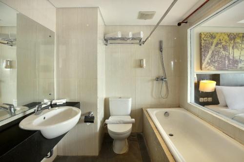 勒吉安Rofa Kuta Hotel - CHSE Certified的浴室配有盥洗盆、卫生间和浴缸。
