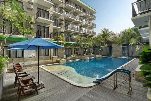 勒吉安Rofa Kuta Hotel - CHSE Certified的一个带遮阳伞和椅子的游泳池以及酒店