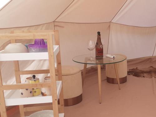 马里蒂玛Farm Glamping tent on Acquaviva Bay的帐篷配有桌子和一瓶葡萄酒