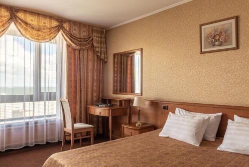莫斯科宇宙酒店的配有一张床、一张书桌和一扇窗户的酒店客房