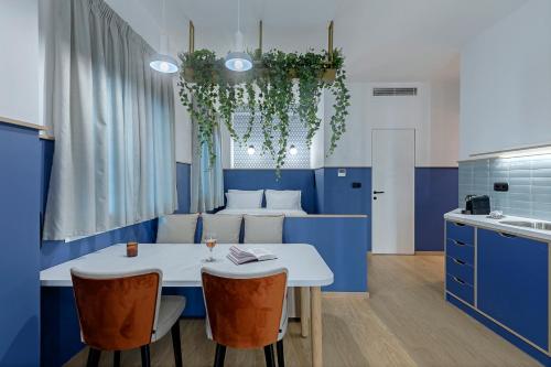 雅典Acro Urban Suites的厨房配有蓝色橱柜和白色的桌椅