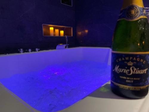 洛里昂Lorient Love Room Le King Size的一瓶葡萄酒,坐在一个紫色液体的浴缸旁