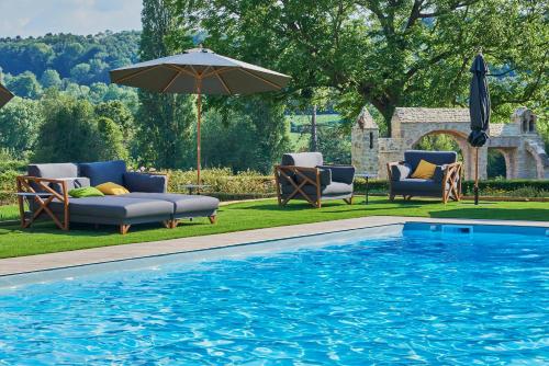 珀内代皮耶Les Jardins de Coppélia的游泳池旁设有椅子和遮阳伞