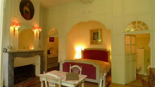 Labastide-dʼArmagnac帕拉达城堡酒店的一间卧室配有一张床、一张桌子和一个壁炉