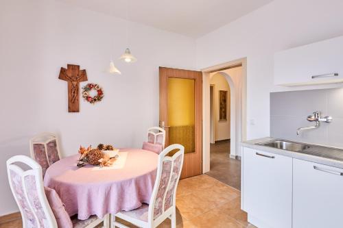NovacellaApartmenthaus Haringer的厨房配有桌子和墙上的十字架