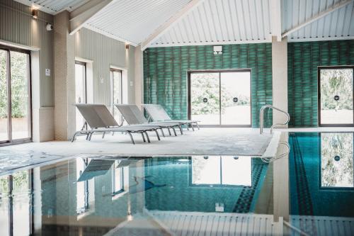 科格索尔埃塞克斯高尔夫&乡村俱乐部酒店的客房设有带椅子和窗户的游泳池。