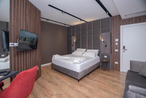 伏罗拉Hotel PortSide GF的一间卧室配有一张床、一台电视和一张沙发