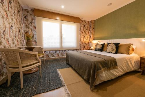 德拉托亚岛Apartamento en la Isla de la Toja的一间卧室设有一张床、一个窗口和一把椅子