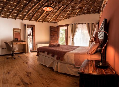 圣佩德罗·德·阿塔卡马Lodge Atacama Horse的一间卧室配有一张床、一张书桌和一个窗户。