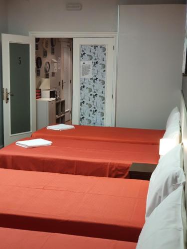 洛格罗尼奥Pensión El Espolón的红色床单的客房内的两张床