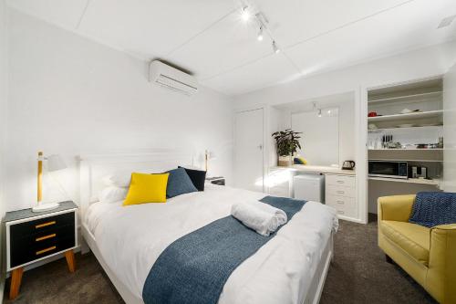 贝纳拉本森旅馆公寓的白色卧室,配有床和黄色椅子