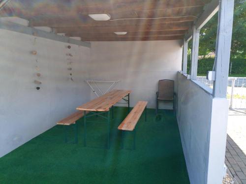 坡瑟利特兹kleines gemütliches Ferienhaus的一张野餐桌和一张长凳,位于一间铺有绿色地毯的房间里