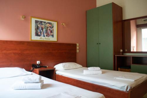 约阿尼纳Egnatia Hotel的配有红色墙壁和绿色橱柜的客房内的两张床