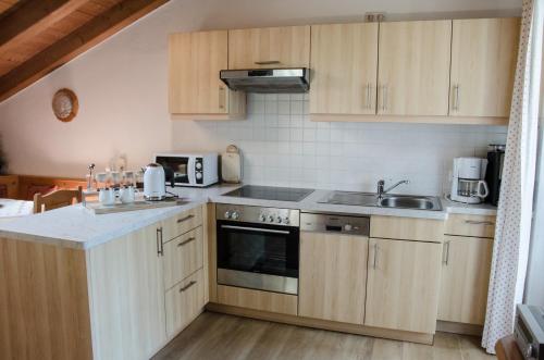 柯尼希斯湖畔舍瑙菲林海德公寓的厨房配有木制橱柜和炉灶烤箱。