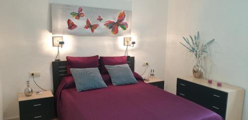 阿尔考斯布里EL Gecko的一间卧室配有一张大床,提供紫色床单和枕头