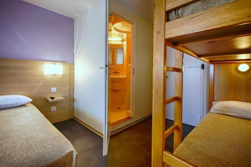 瑟农方程式俱乐部酒店的一间小卧室,配有双层床和镜子
