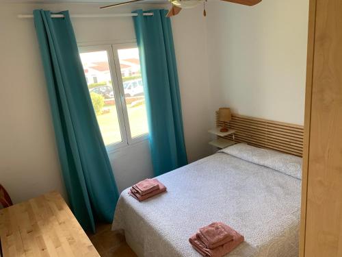 阿雷纳尔登卡斯特尔Ca la Marta apartamento con piscina y jardín a 150m de la playa的一间卧室配有一张带蓝色窗帘的床和一扇窗户