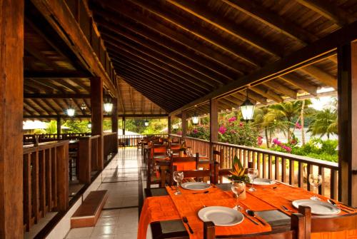 巴亚索拉诺Playa de Oro Lodge的阳台餐厅,配有木桌椅