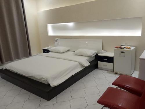 阿吉曼Corniche Palace Hotel的一间卧室配有一张床和一张红色椅子