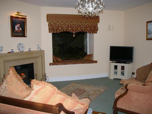 诺曼顿The Grange的客厅设有壁炉和电视。