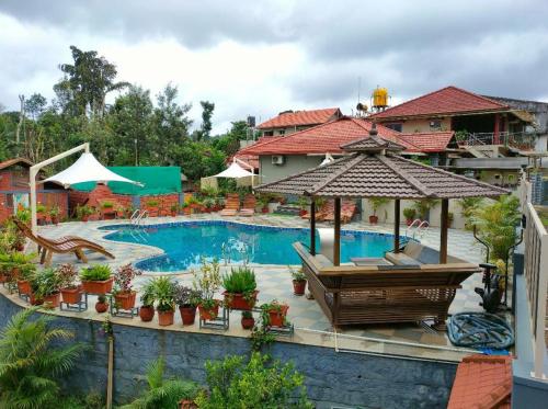 马迪凯里Srinikethana Home Stay with Swimming Pool的一个带遮阳伞和椅子的游泳池的度假酒店