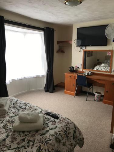韦茅斯Dolphin Hotel Public House Weymouth的一间卧室配有一张床、一张书桌和一台电视