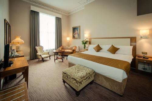 都柏林阿尔班尼酒店的酒店客房设有一张大床和一张书桌。