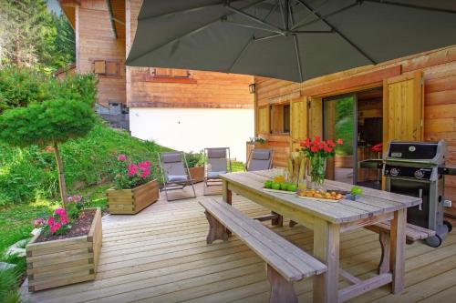 拉克吕萨Chalet Charmar - OVO Network的木甲板配有桌子和遮阳伞