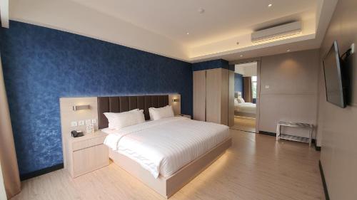 巨港克拉西酒店的一间卧室设有一张大床和蓝色的墙壁