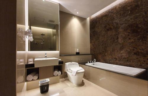 巨港克拉西酒店的浴室配有卫生间、盥洗盆和浴缸。