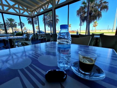 弗尼迪克Hotel La Corniche Fnideq的一瓶水和一张桌子上的玻璃杯