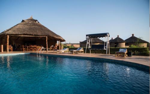 瓦加杜古格兰德卡劳宾馆的一个带茅草小屋和椅子的大型游泳池