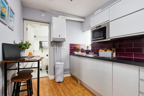 达宁顿堡Delven House, Apartment 5的厨房配有白色橱柜和1张带笔记本电脑的桌子。