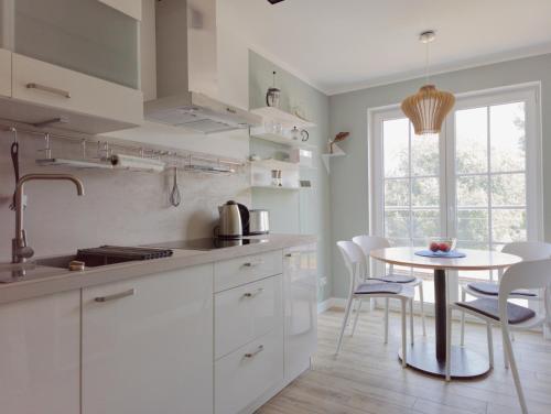 普特布斯Jolle 54的厨房配有白色橱柜和桌椅