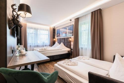 安达赫治Hotel Demas München-Unterhaching的酒店客房设有两张床和一张桌子。